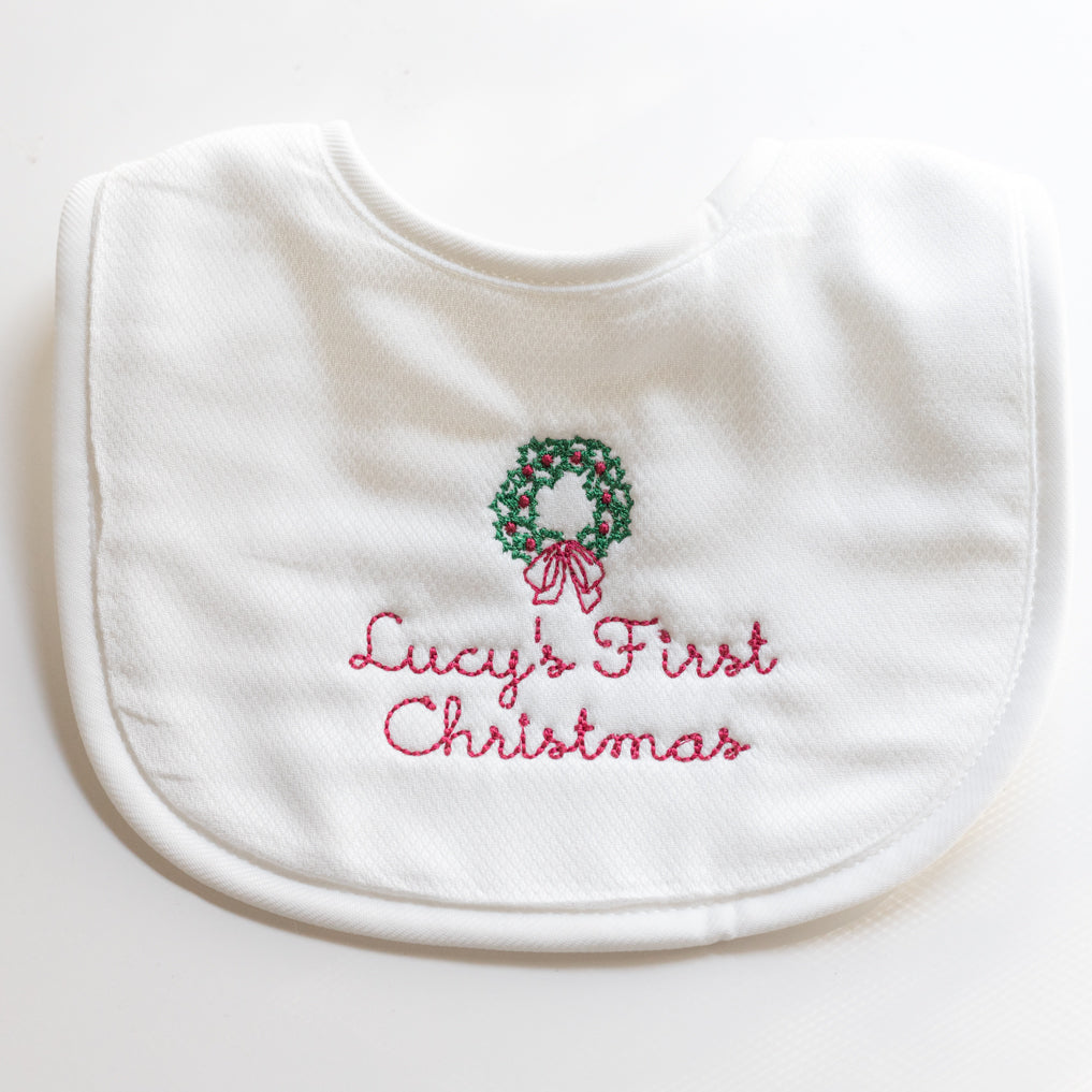 Personalized baby’s first Christmas bib with embroidered name and wreath in traditional green and red colors