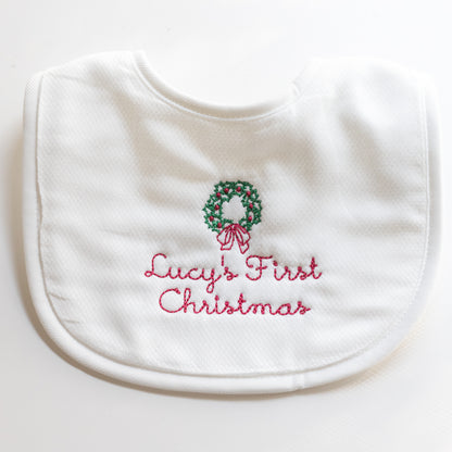 Personalized baby’s first Christmas bib with embroidered name and wreath in traditional green and red colors